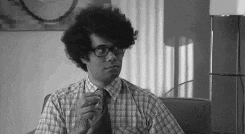 a black and white photo of a man with curly hair wearing glasses and a plaid shirt .