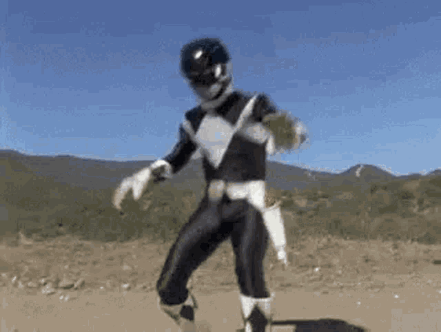 a black ranger from power rangers is dancing in a dirt field .