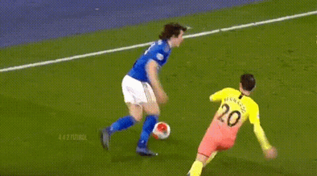 a soccer player in a blue uniform is running with the ball while a goalie in a yellow uniform is standing behind him .