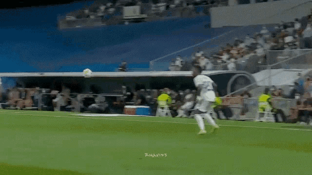 a soccer player is kicking a soccer ball on a field while a crowd watches .