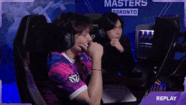 a man wearing headphones sits in front of a screen that says replay