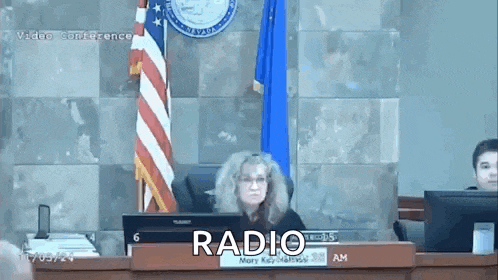 a woman is sitting at a desk in front of a sign that says radio
