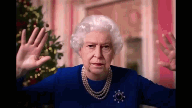 queen elizabeth ii is wearing a blue dress and pearls and is making a funny face .