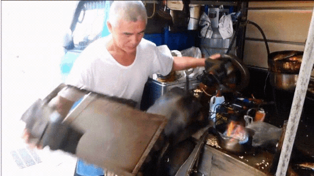 a man in a white shirt is standing in a kitchen holding a piece of metal