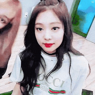 a girl with long black hair is wearing a white gucci t-shirt and a choker .