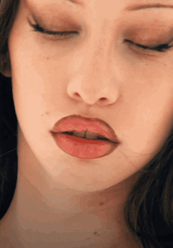a close up of a woman 's face with red lips and her eyes closed