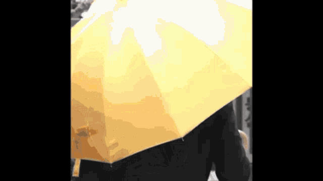 a person is holding a yellow umbrella while walking in the rain