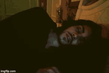 a man with long hair and a beard is laying on a bed with his eyes closed ..