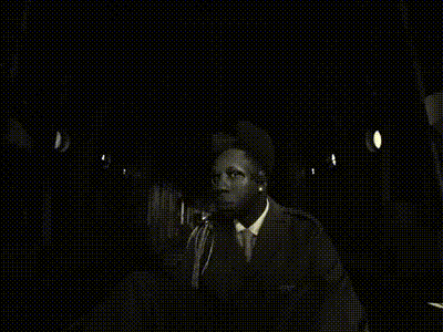 a black and white photo of a man in a suit sitting on a chair