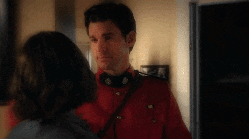 a man in a red uniform looks at a woman