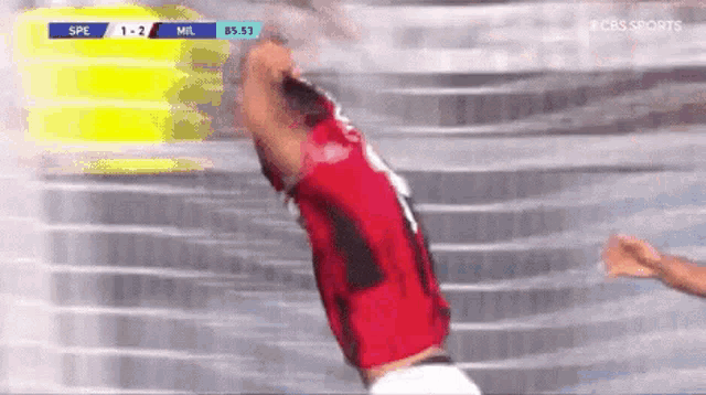 a soccer player in a red jersey is jumping in the air during a game .