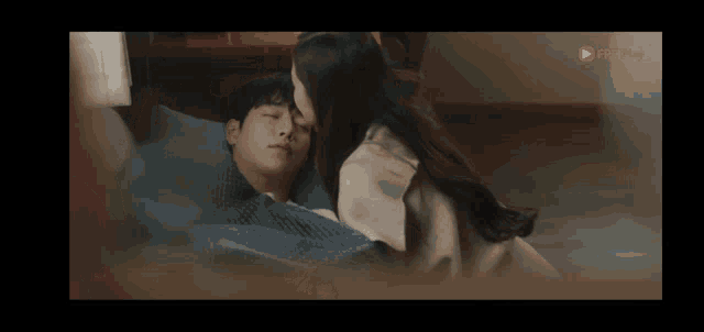 a woman is kissing a man on the forehead while they are laying in bed .