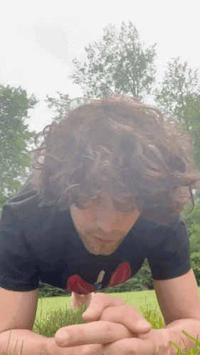 a man with curly hair wearing a black t-shirt with a rolling stones logo on it
