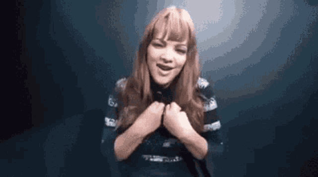 a woman with long red hair is making a funny face while holding her hands to her chest .