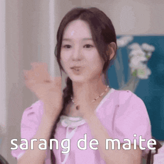 a girl in a pink shirt is clapping her hands and says sarang de maite .
