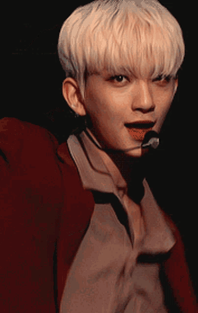 a man with blonde hair is wearing a red jacket and tie