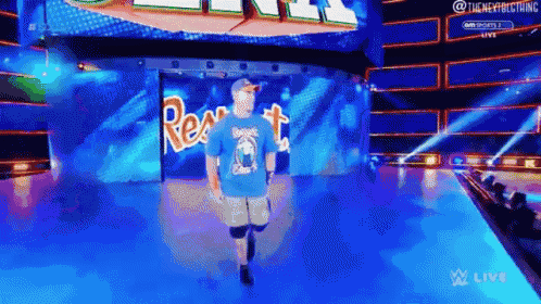 a man in a blue shirt is walking on a stage in front of a large screen .