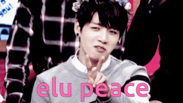 a young man with a flower crown on his head giving a peace sign and the words elu peace behind him