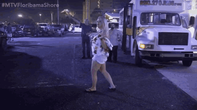 a woman is walking in front of a white truck that says ' florida shore ' on the front