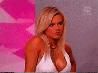 a woman with a very large breast is sitting in front of a pink background .