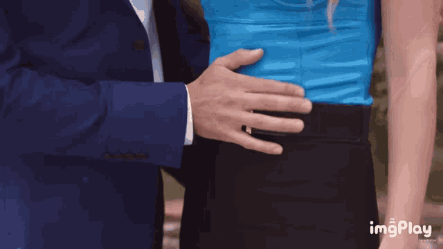 a man in a suit is touching the back of a woman 's waist with his hand