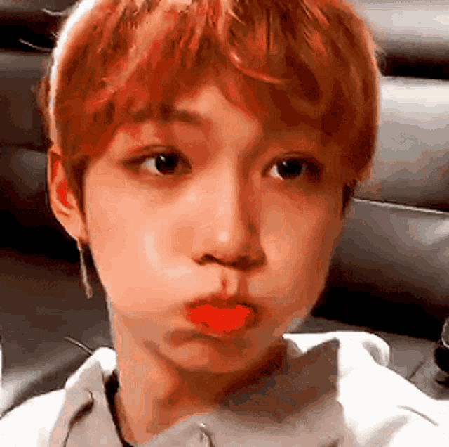 a young man with red hair is making a face with his mouth open .