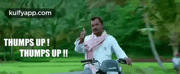 a man is riding a motorcycle down a road and giving a thumbs up .