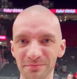 a close up of a bald man 's face with a beard .
