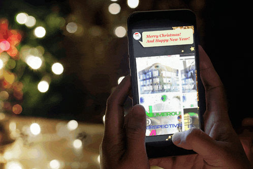 a person holding a cell phone with a merry christmas message on it