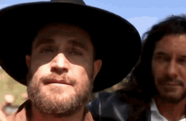 a man with a beard wears a black hat