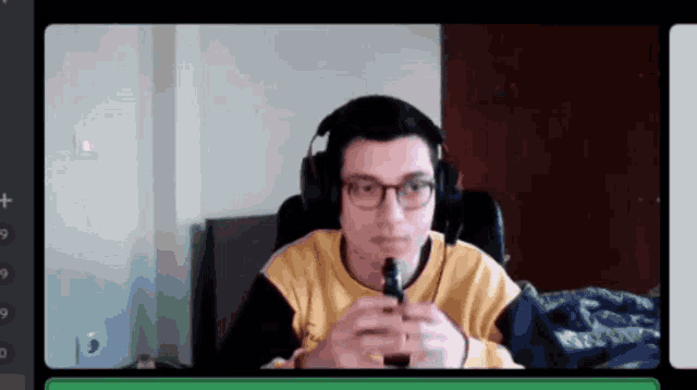 a man wearing headphones and glasses is holding a vape in his hand .