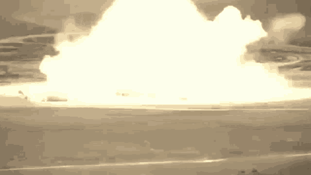 a large explosion is taking place in the middle of a field in a black and white photo .
