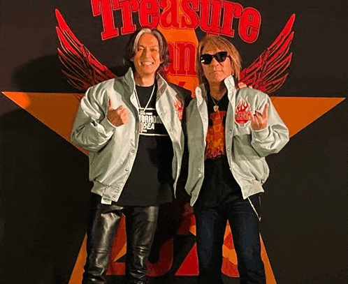 two men are standing next to each other in front of a large star with the word treasure on it .