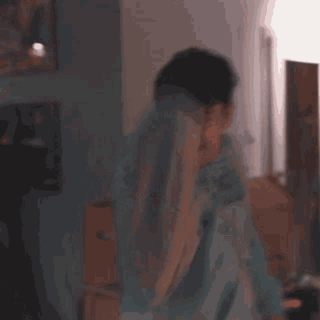 a man in a blue hoodie is standing in a living room with a box in the background .