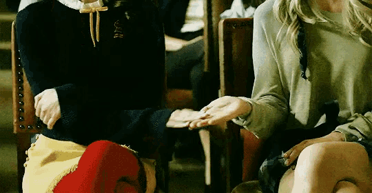 a woman in a green sweater holds the hand of another woman in a black sweater