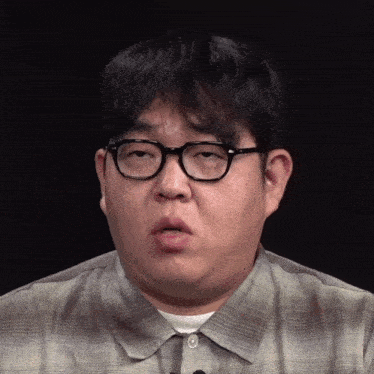 a man wearing glasses and a plaid shirt is making a face