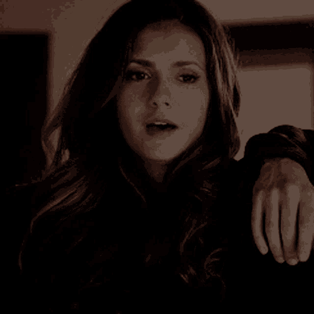 a close up of a woman 's face with her hand resting on her shoulder