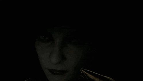 a close up of a woman 's face in the dark with a smile on her face .