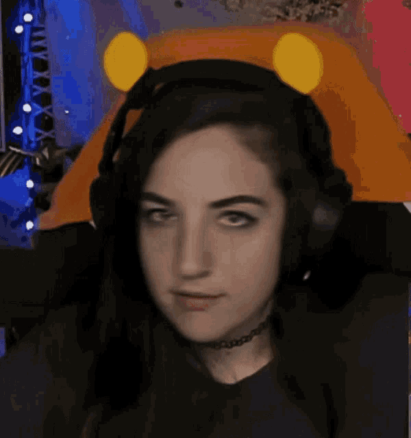 a woman wearing headphones and a choker is sitting in a chair