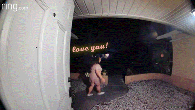 a woman walking in front of a door that says ring.com