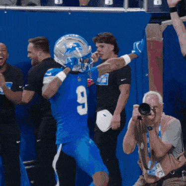 a man taking a picture of a football player wearing a number 9 jersey
