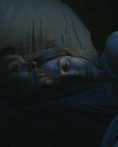 a man and a woman are laying in a dark room