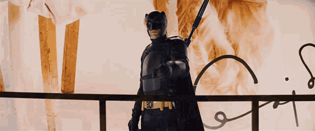 a man in a batman costume is holding a sword