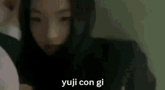 a blurry picture of a woman wearing a black hoodie with the words `` yuji con gi '' written on the bottom .
