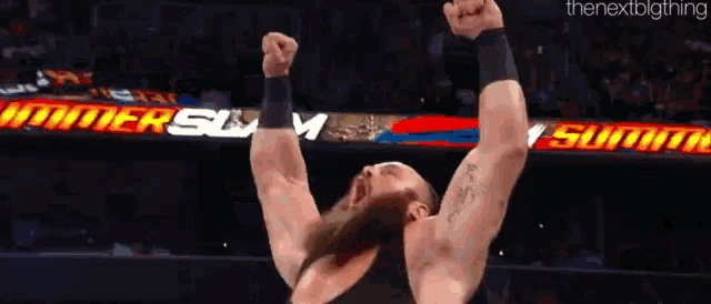 a wrestler with his arms in the air in front of a sign that says ' summerslam '