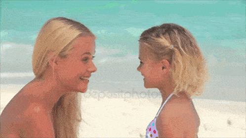 a mother and daughter looking at each other on the beach