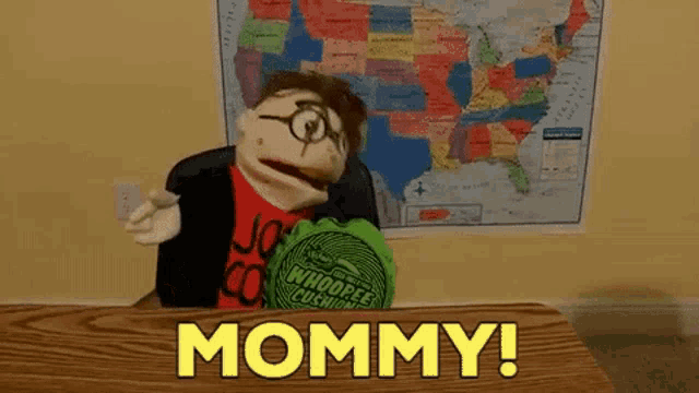 a puppet is sitting at a desk in front of a map and says mommy !