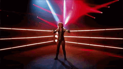 a woman is standing in a boxing ring with red lights behind her