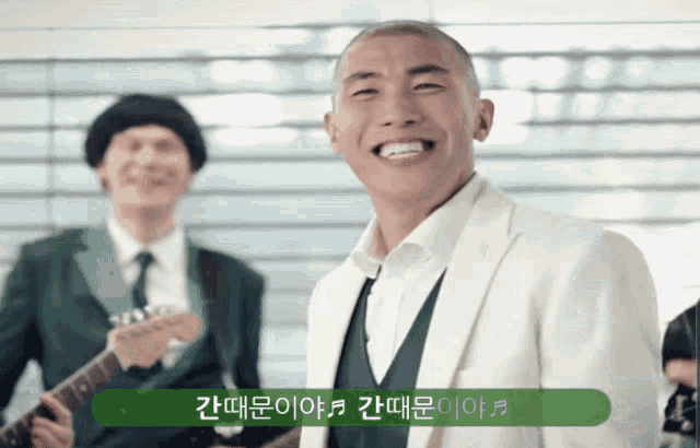 a man in a white suit is smiling in front of a group of men
