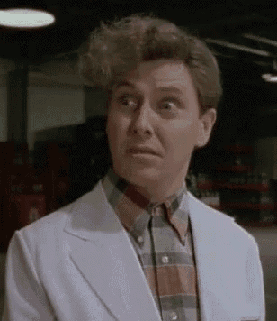a man in a white suit and plaid shirt is making a funny face in a garage .